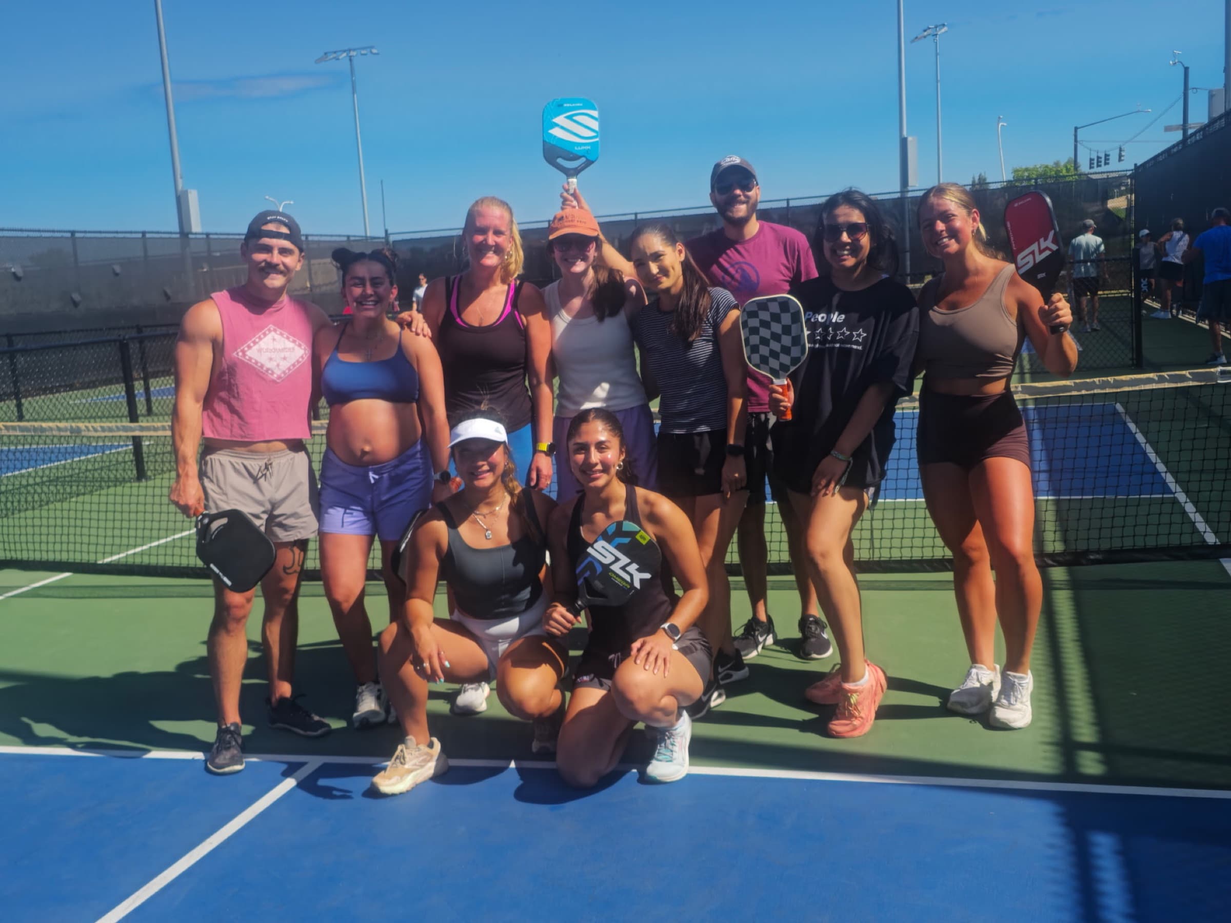 Elevate members holding paddles on the pickleball courts at John Venezia Park